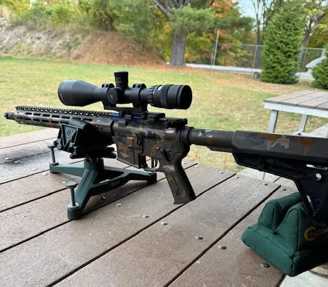 Camo precision rifle with scope on benchrest