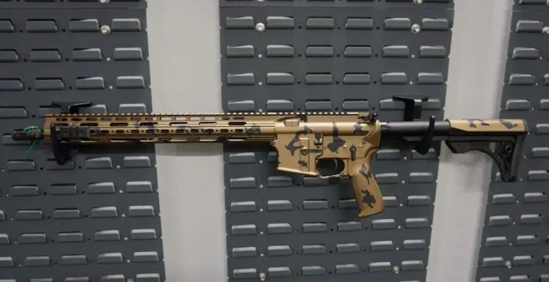 A camouflaged assault rifle mounted on a wall.