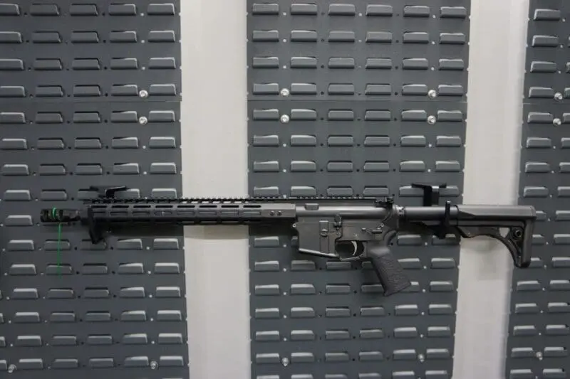 A modern black semi-automatic rifle displayed against a gray pegboard.