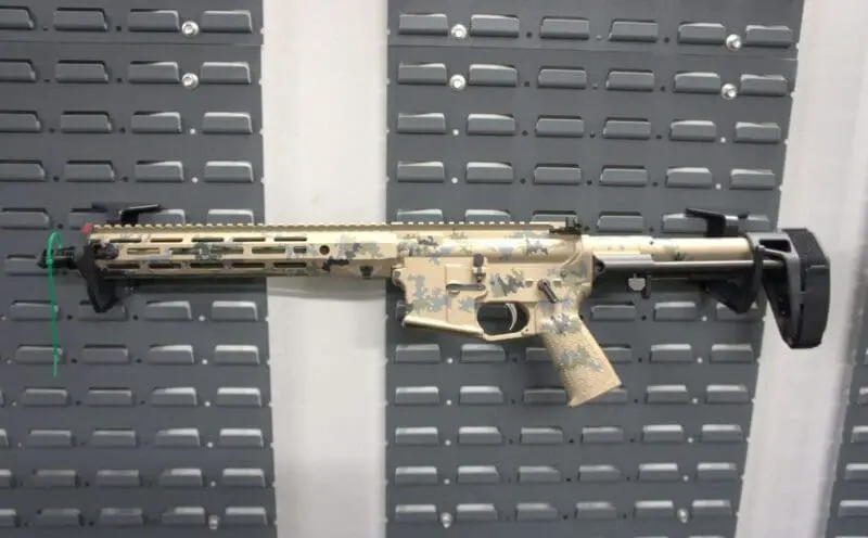 A camouflaged assault rifle displayed against a gray background.