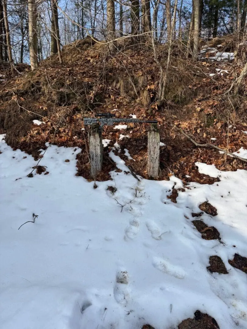 Boot prints in snow toward weathered posts