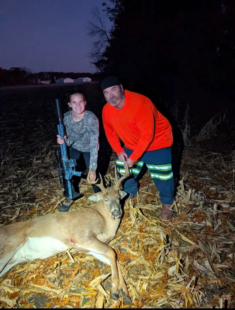 Two hunters posing with deer and rifle